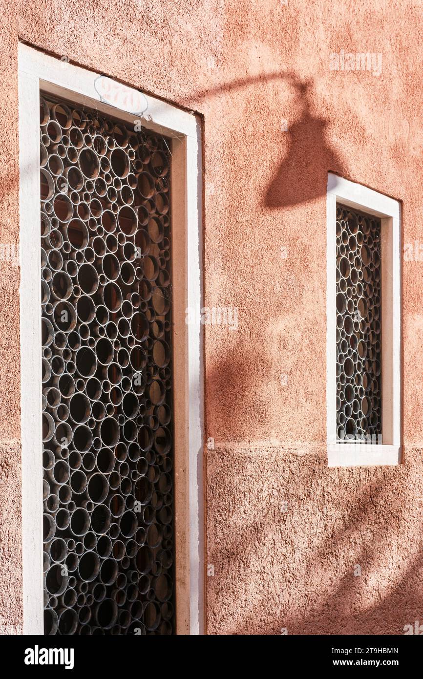 Venezia, Italia - 9 novembre 2023: Dettaglio architettonico di ornamenti circolari in ferro battuto su finestre e porte aperte con parete rosa Foto Stock