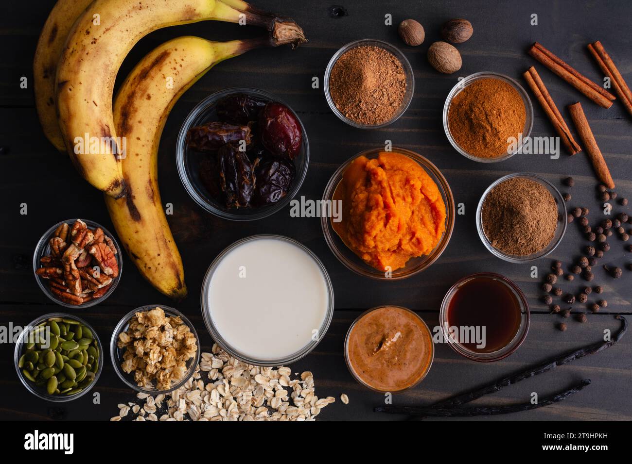 Ciotola per frullato di zucca ingredienti su un tavolo di legno: Purea di zucca, datteri, burro di mandorle e altri ingredienti per una colazione vegana con frullato Foto Stock