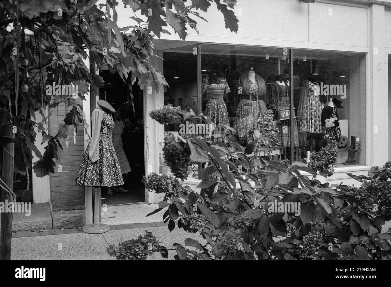 Salem, Massachusetts - Un luminoso negozio boutique pieno di abiti vintage in mostra per i turisti con fiori in fiore in primo piano. La i Foto Stock