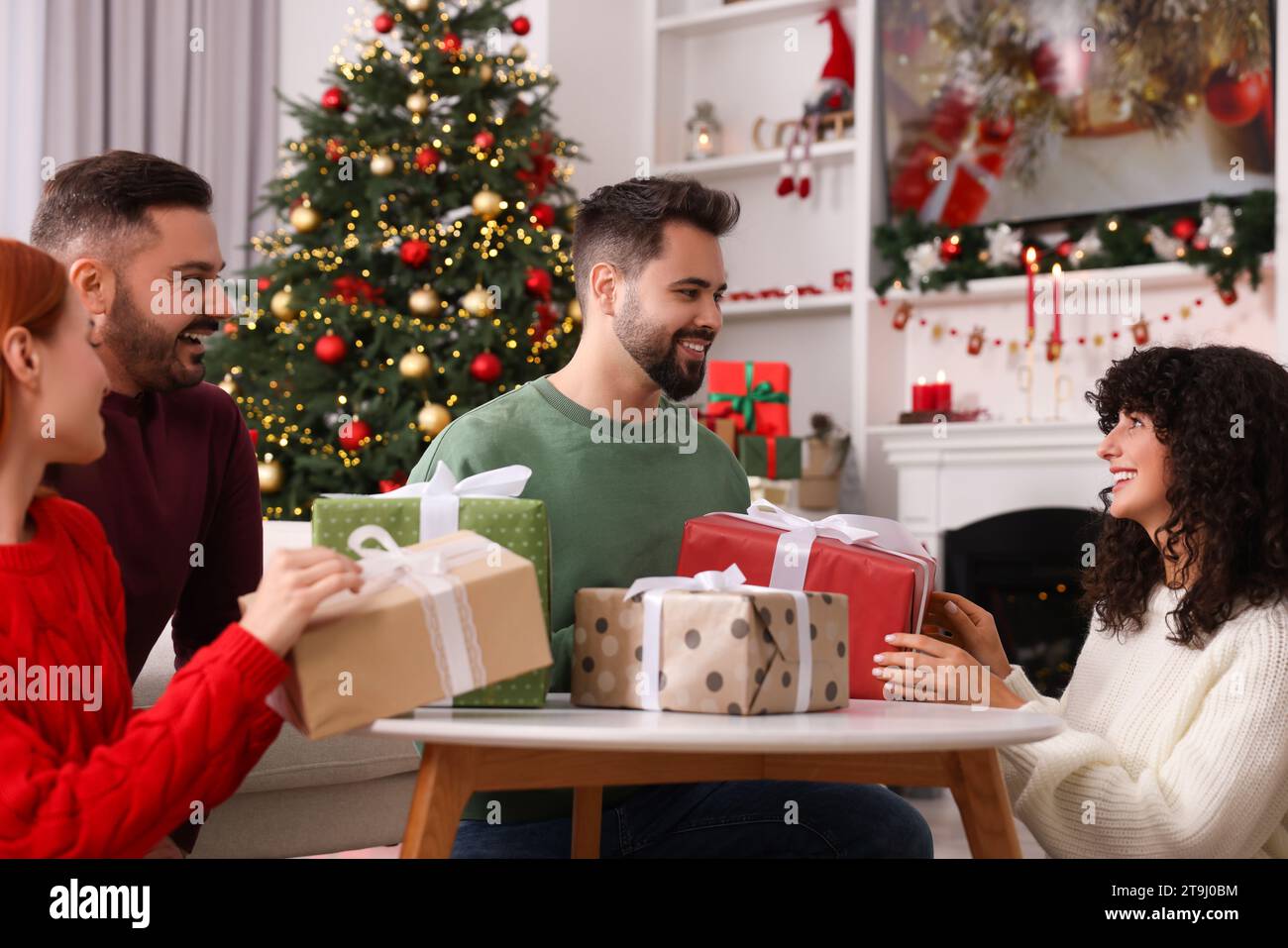 Amici felici che si scambiano regali di Natale a casa Foto Stock