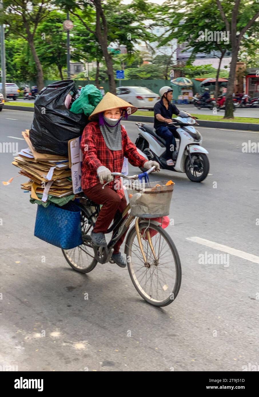 Ho chi Minh Traffic, Vietnam. Ciclista che trasporta rifiuti riciclabili al centro di riciclaggio. Foto Stock