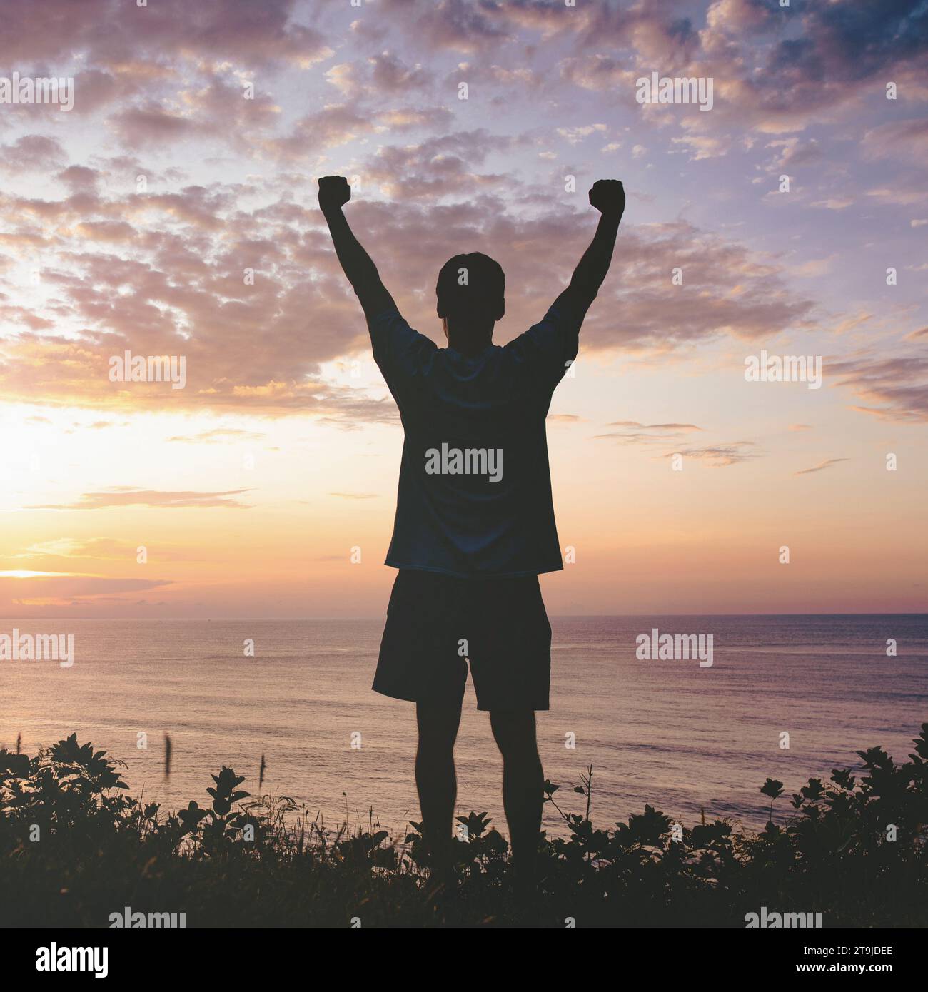 L'uomo che alza i pugni sul cielo del tramonto. La vittoria e il trionfo della gente. Foto Stock