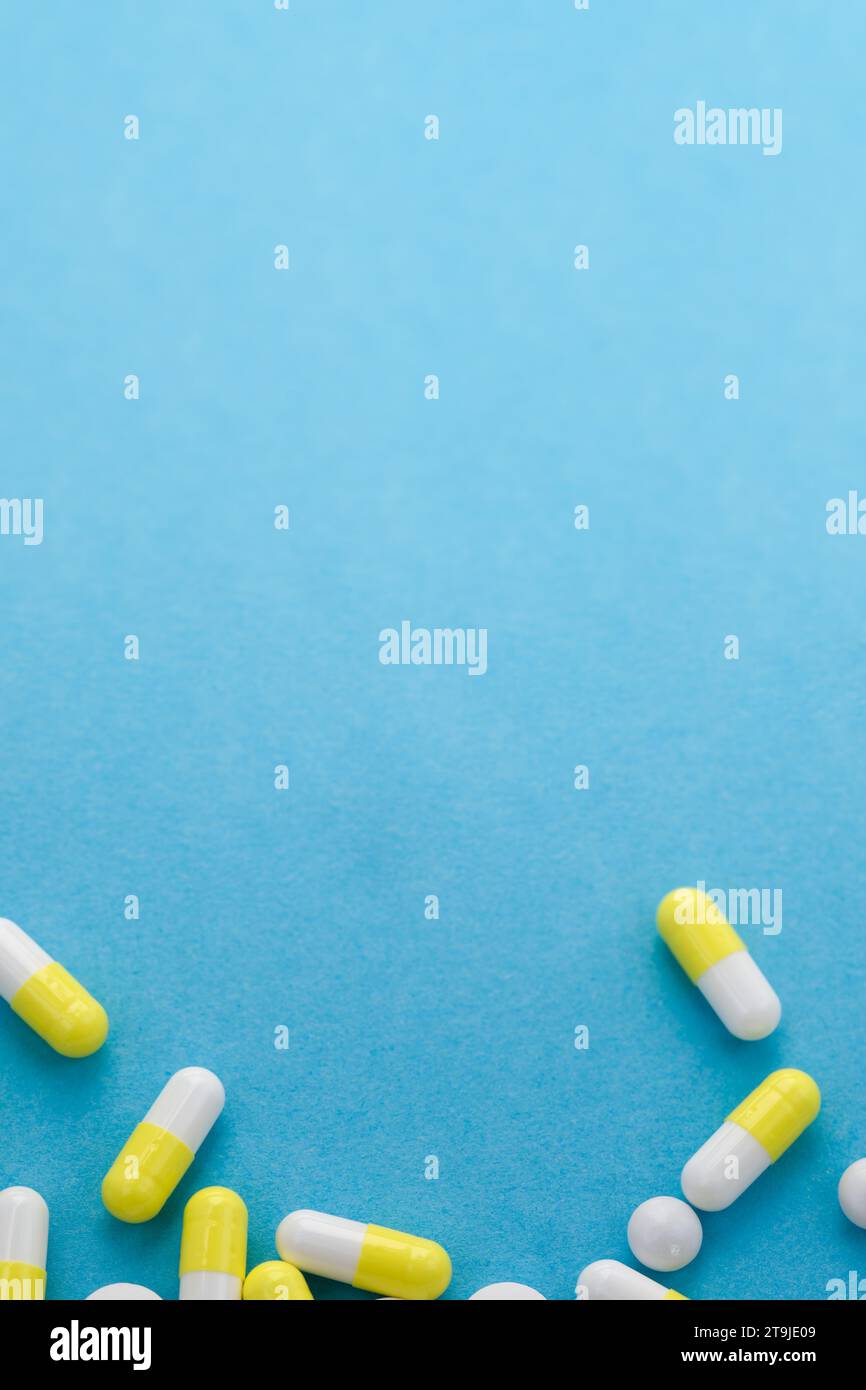 Pillole bianche e gialle assortite su tavolo blu. Concetto medico, farmaceutico e sanitario. Copia spazio. Spazio vuoto per testo o logo. Foto Stock