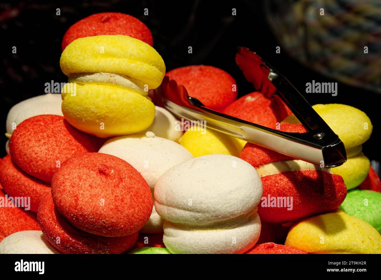 Un primo piano di macaron colorati con un paio di pinze sulla parte superiore. Foto Stock