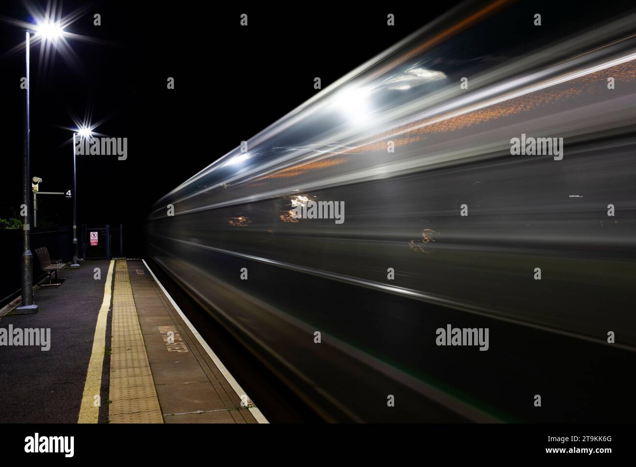 Lunga esposizione del treno che si muove lungo la piattaforma di notte a Newcourt Exeter Regno Unito Foto Stock