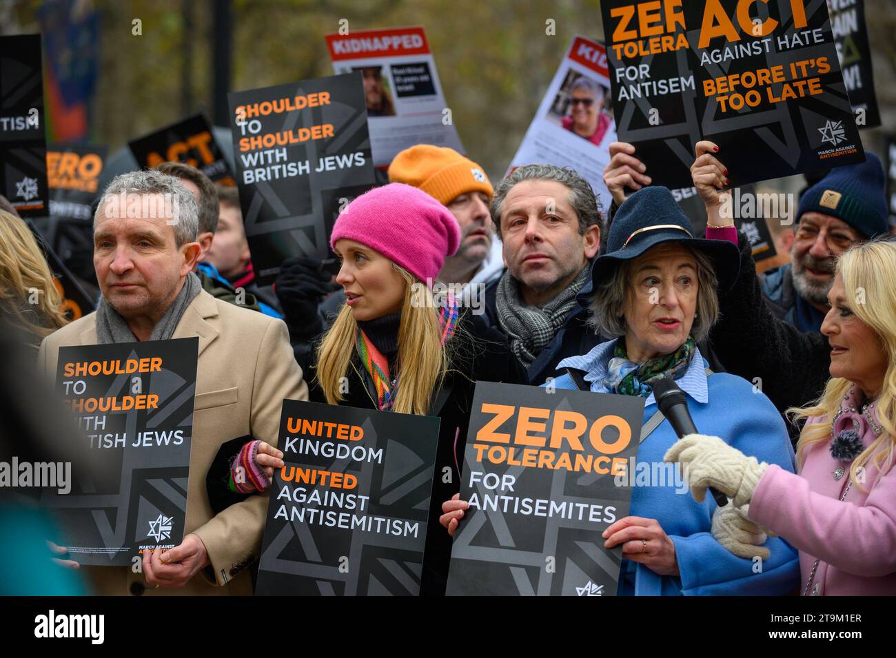 Migliaia di persone marciano contro l'antisemitismo a Londra, con figure di spicco che guidano la marcia, tra cui il rabbino capo e molti attori. Un uomo ha arrestato e messo in furgone della polizia. Foto Stock