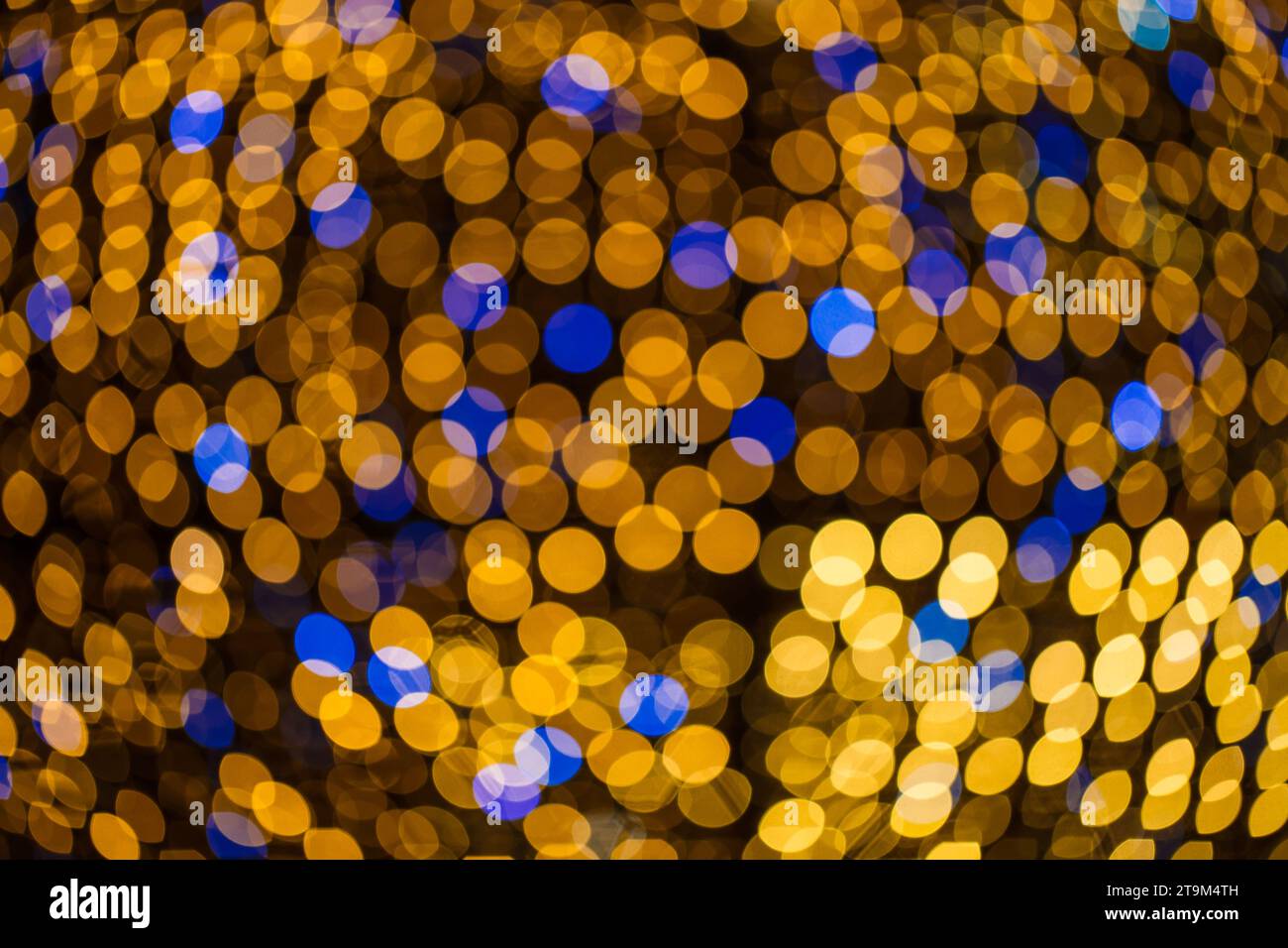 Riflessi delle luci gialle e blu sfocati, forma sferica, sfondo. Effetto bokeh. Foto Stock