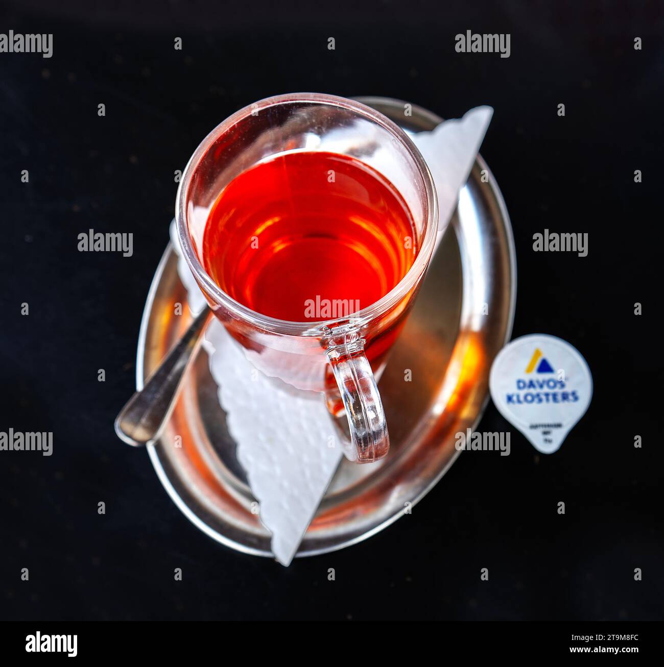 Tazza di tè in vetro su un piccolo vassoio ovale in metallo lucido con un piccolo cartone per il latte Foto Stock