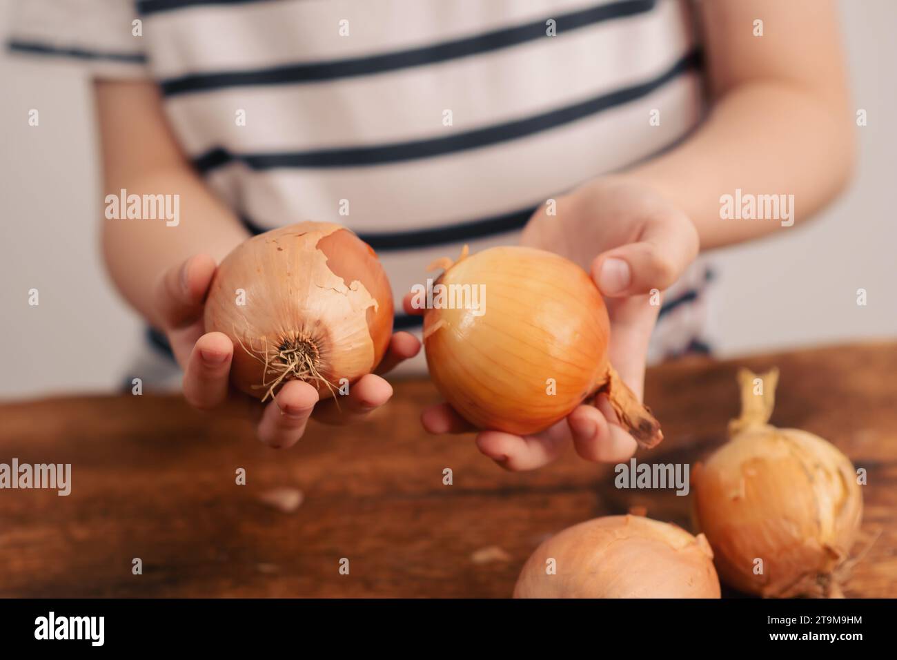 Assaporate il sapore: Un bambino presenta con orgoglio una cipolla completa, sottolineando il valore nutrizionale e la bontà di incorporare le cipolle nei pasti Foto Stock