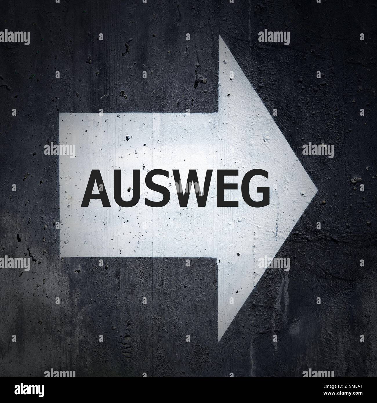 Freccia direzionale bianca su una parete di cemento con l'iscrizione tedesca Ausweg. Traduzione: Via d'uscita Foto Stock