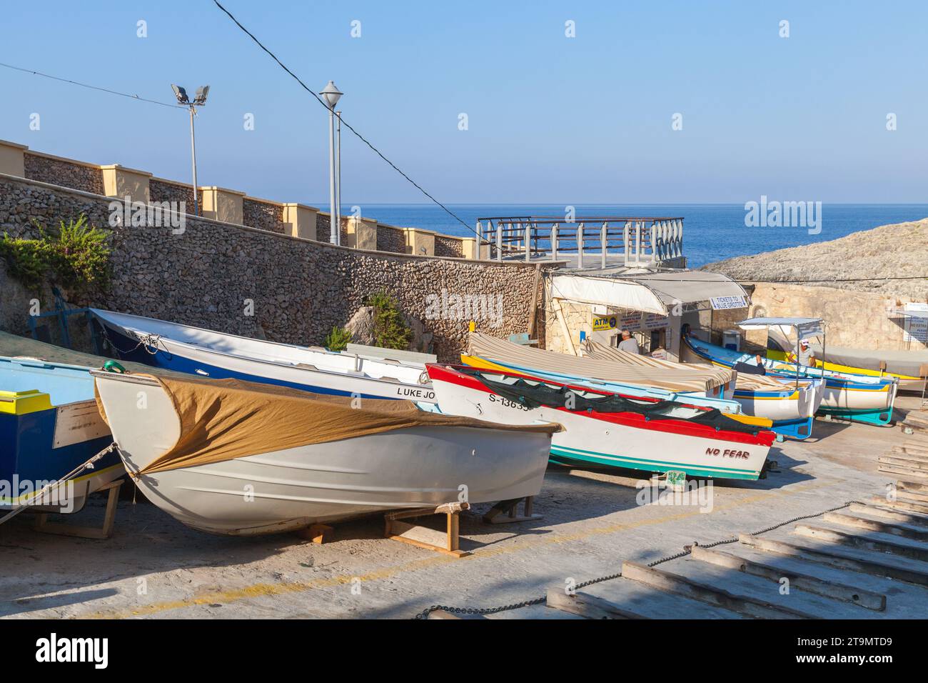 Blue Grotto, Malta - 22 agosto 2019: Vista sulla strada con il tragitto per le gite alla Grotta Azzurra Molo di partenza. Barche di legno si stendevano lungo la strada su un soleggiato Foto Stock