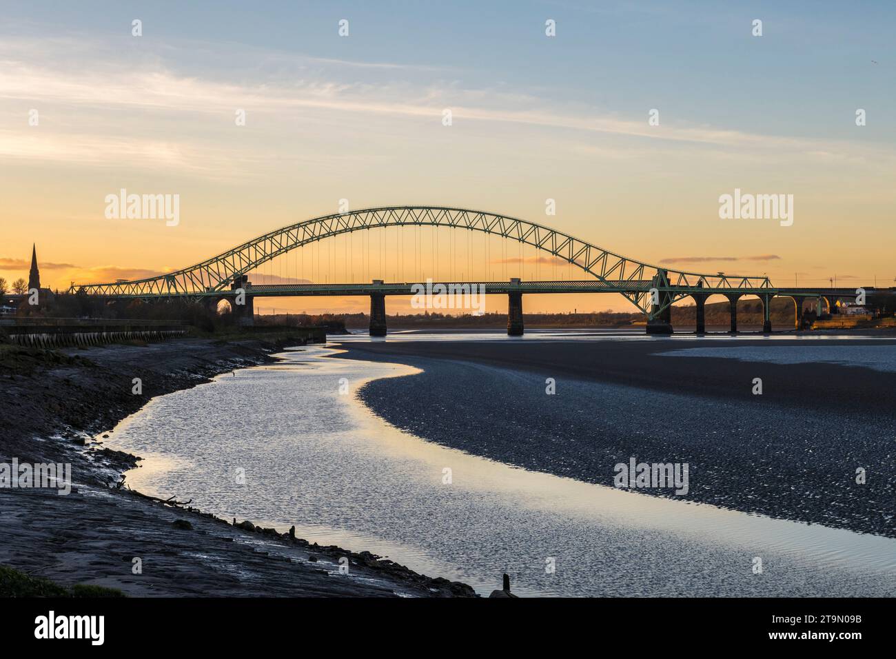 Tramonto dietro il Silver Jubilee Bridge (aperto nel 1961), che attraversa il fiume Mersey e il Manchester Ship Canal, collegando Runcorn e Widnes Foto Stock