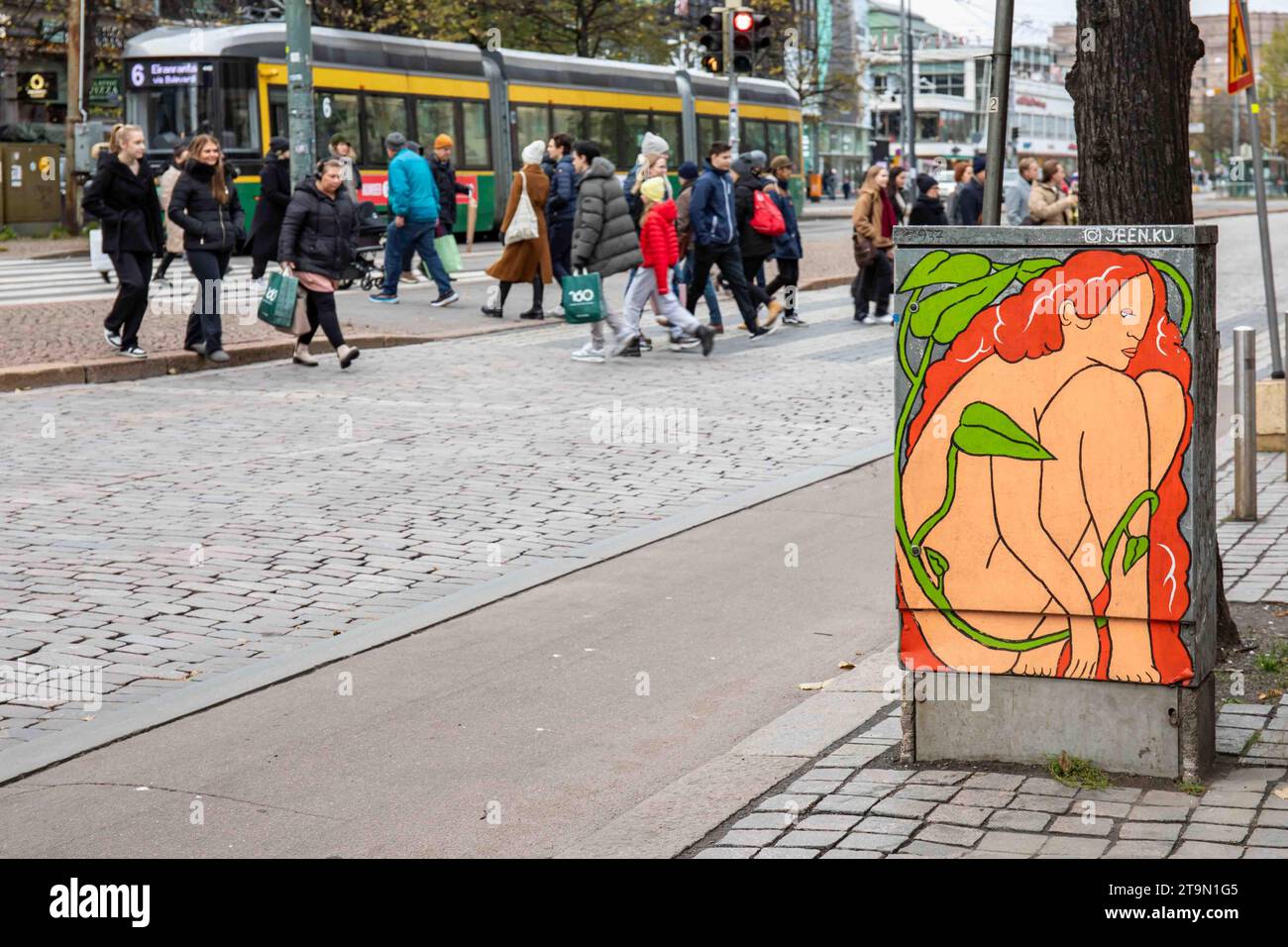 Arte di strada su armadietto di strada con persone che attraversano Mannerheimintie sullo sfondo a Helsinki, Finlandia Foto Stock