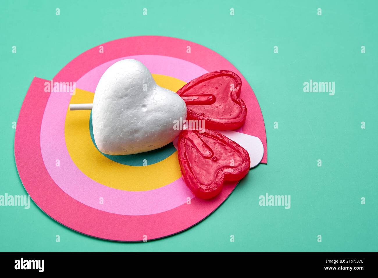 Due lecca lecca-lecca rossi sulla sommità di un arcobaleno con un cuore bianco puro. Concetto di amore puro. Foto Stock