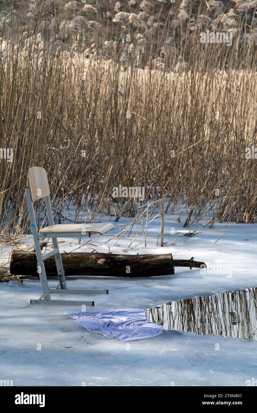 Foto che mostra una sedia in piedi su un lago coperto di ghiaccio per la pesca, il fiume, l'hobby, il tempo, lo scioglimento, atmosfera, calma Foto Stock