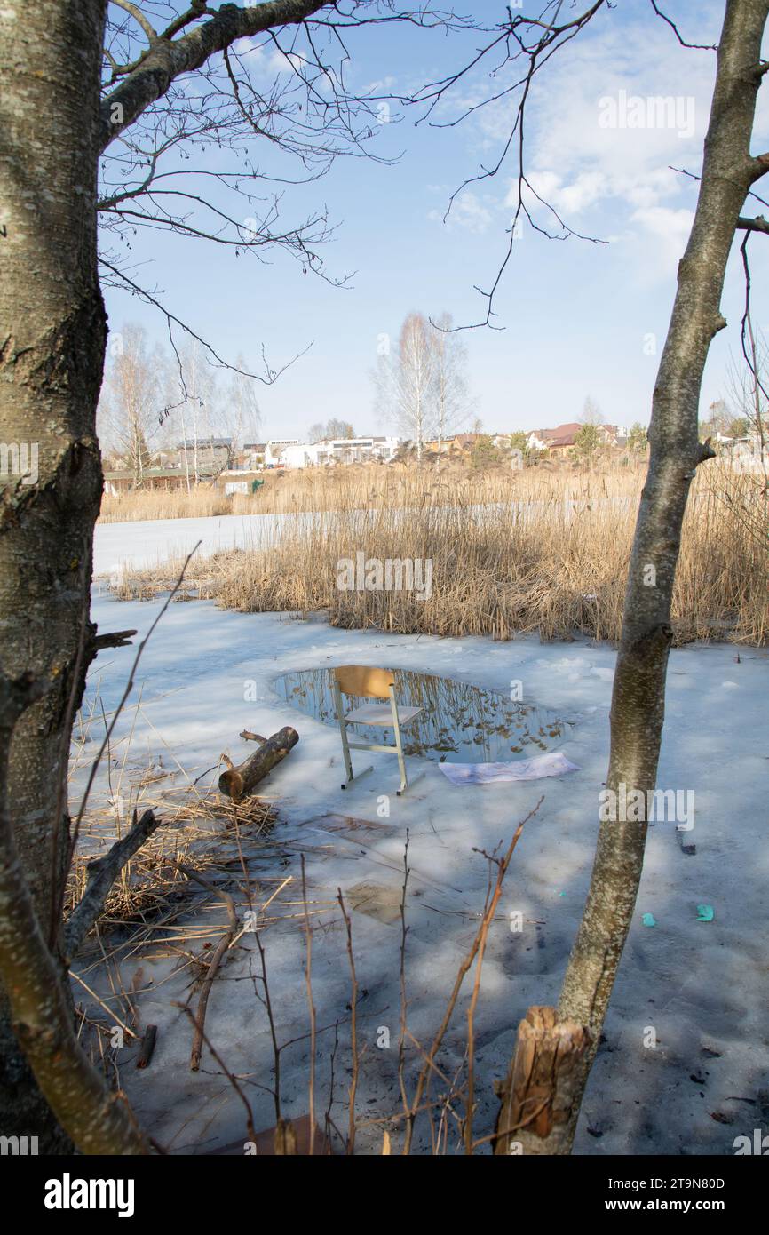 Foto su un lago ricoperto di ghiaccio in crosta c'è una sedia e c'è un buco nel ghiaccio per la pesca, il lago, il giorno, l'atmosfera, attivo, relax, temperamento freddo Foto Stock