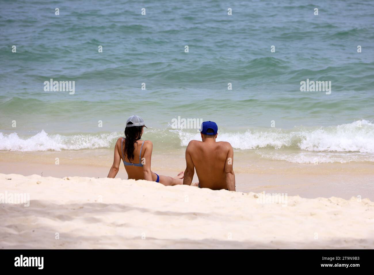 Coppia seduta su una sabbia su fondo mare. Uomo e donna in costume da bagno insieme, vacanza romantica e vacanza al mare Foto Stock