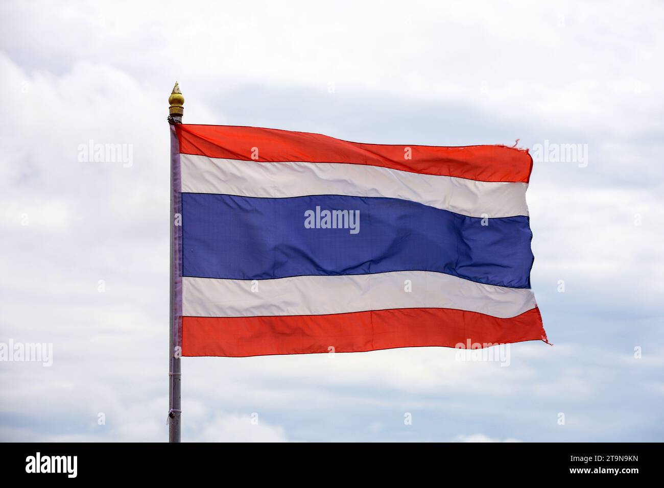 La bandiera nazionale del Regno di Thailandia sventola contro il cielo con le nuvole Foto Stock
