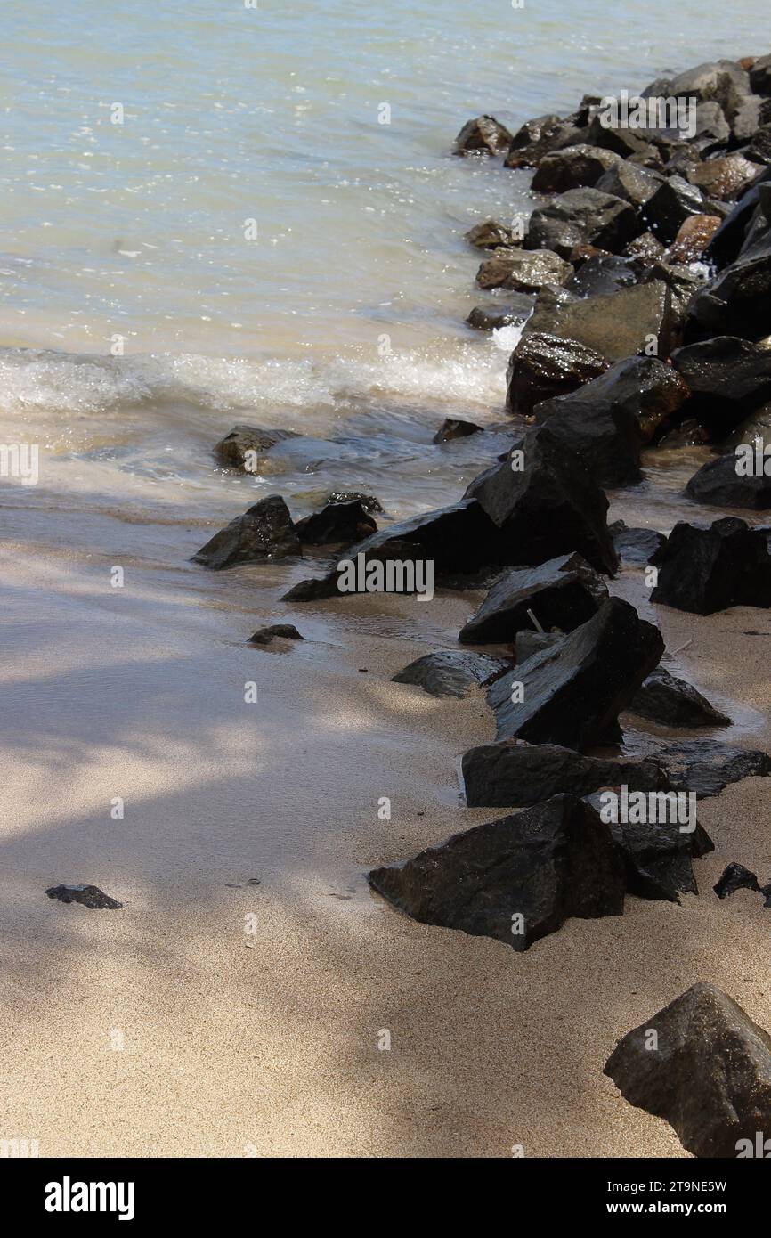 Vista mare, paesaggio naturale composto da elementi di natura costiera, con pietre ruvide, onde marine e sabbia al bordo della spiaggia. Foto Stock