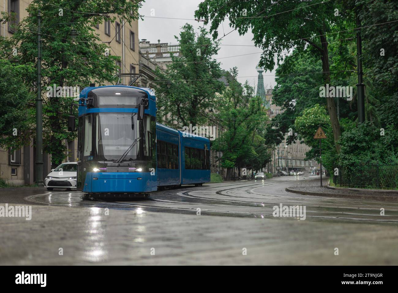 Tram blu polacco nel centro della città di Cracovia in un giorno di pioggia. Bella foto di un tram, servizio pubblico di trasporto durante una leggera pioggia Foto Stock