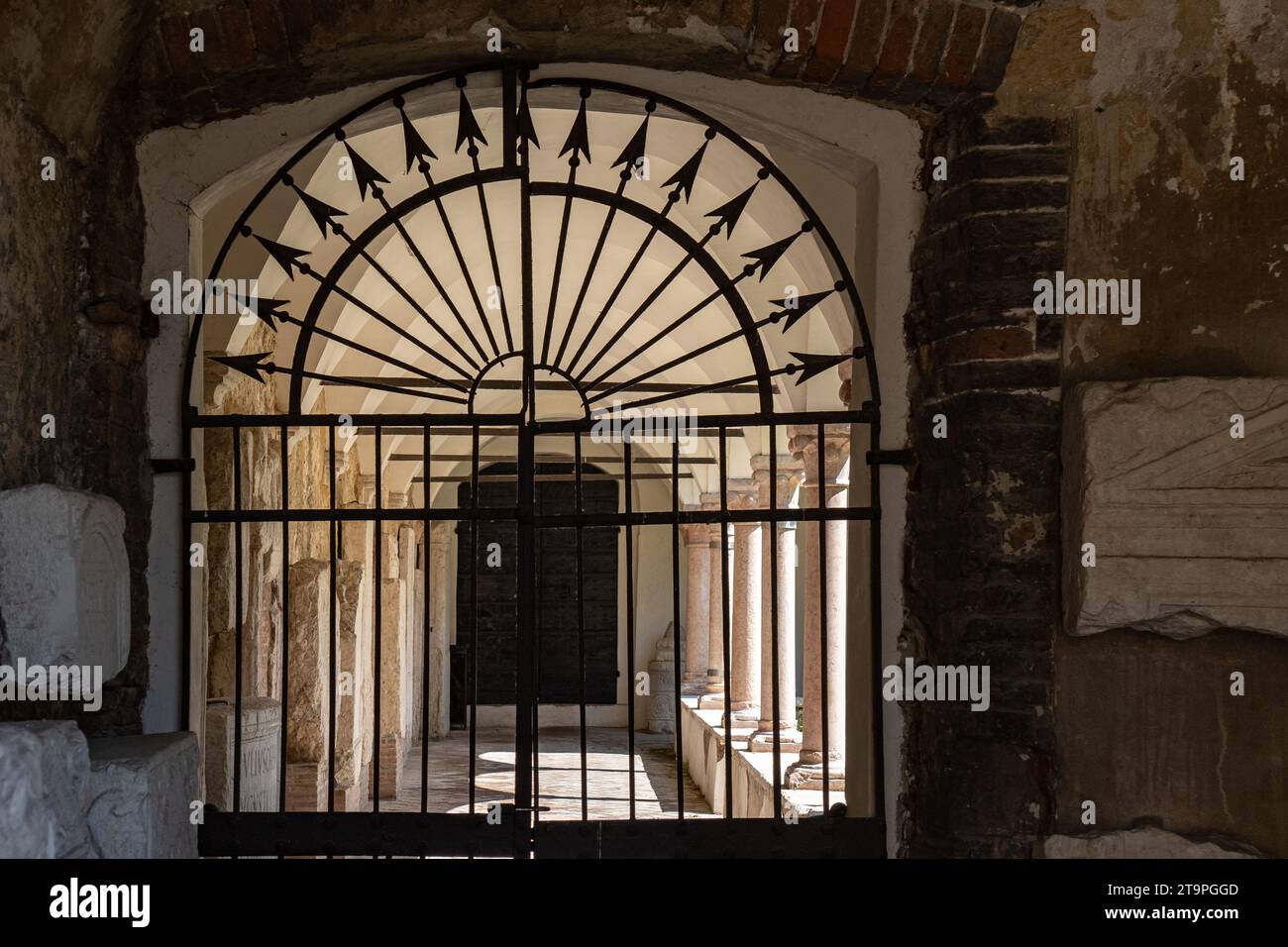 Cancello chiuso in ferro battuto che conduce al corridoio ad arco con colonne su entrambi i lati Foto Stock