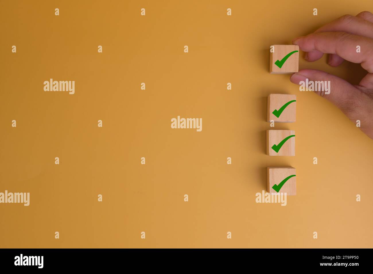 Mano umana che mette cubo in legno con icona segno di spunta su sfondo giallo con concetto di lista di controllo spazio di copia. Foto Stock