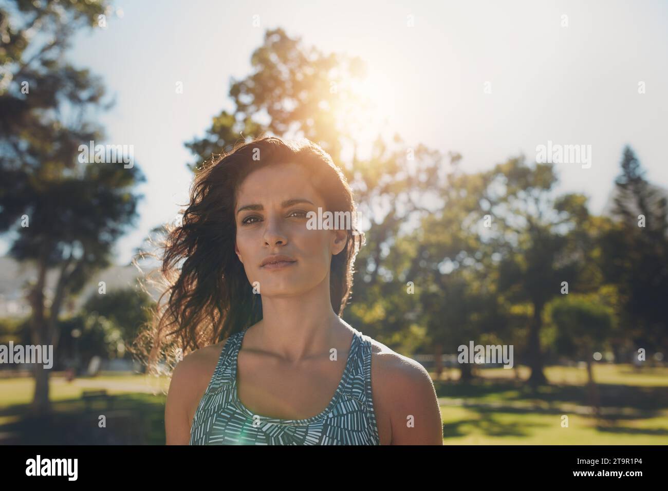 Foto ravvicinata di una bella donna del fitness nel parco. Giovane donna del Medio Oriente sicura di sé che indossa abbigliamento sportivo e si prende una pausa dalla sessione di allenamento all'aperto. Foto Stock