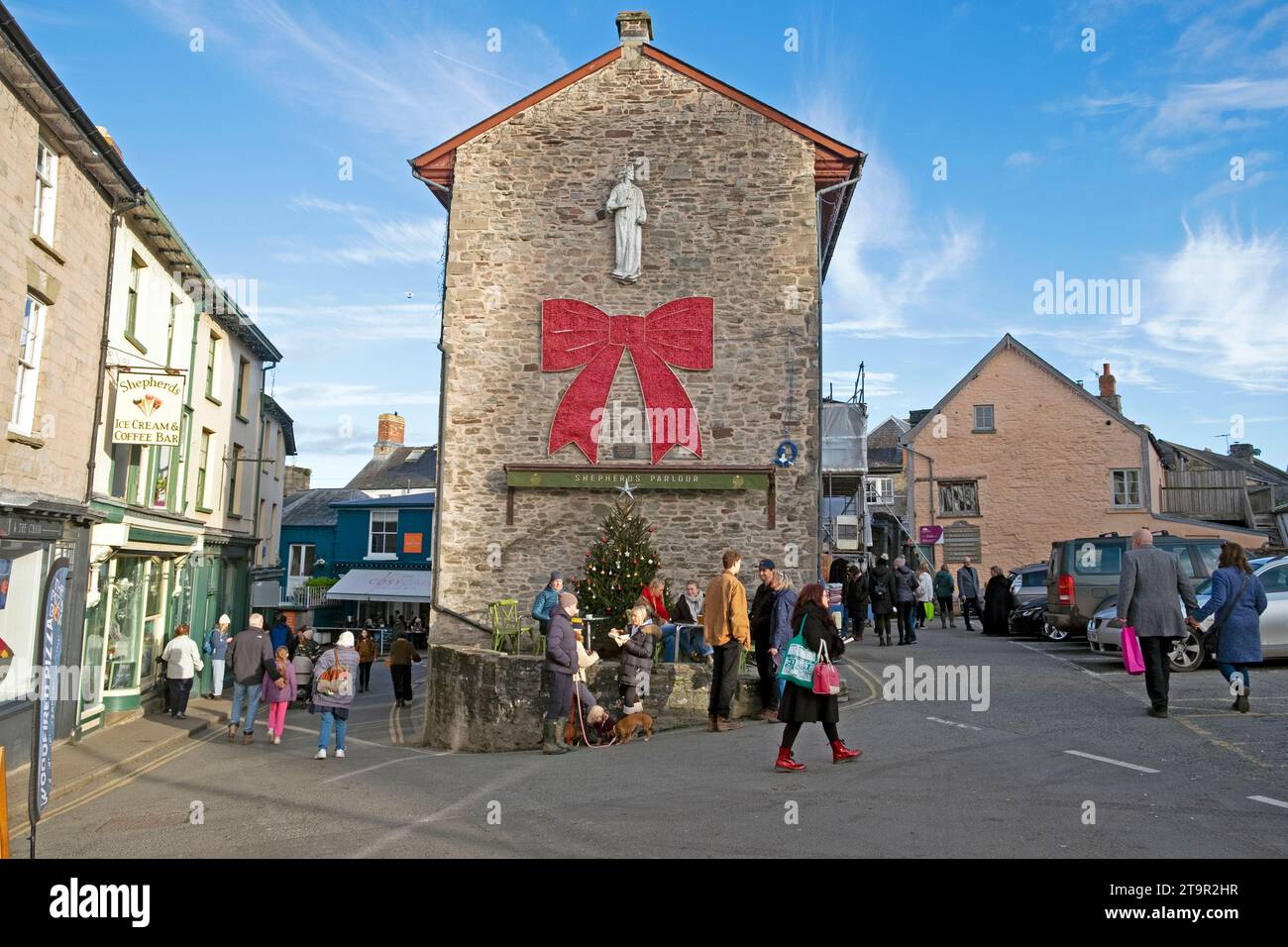 Hay-on-Wye book Town Hall arco rosso, albero di Natale e gente che cammina in piazza durante il festival del libro Hay Winter Festival in Galles, UK KATHY DEWITT Foto Stock