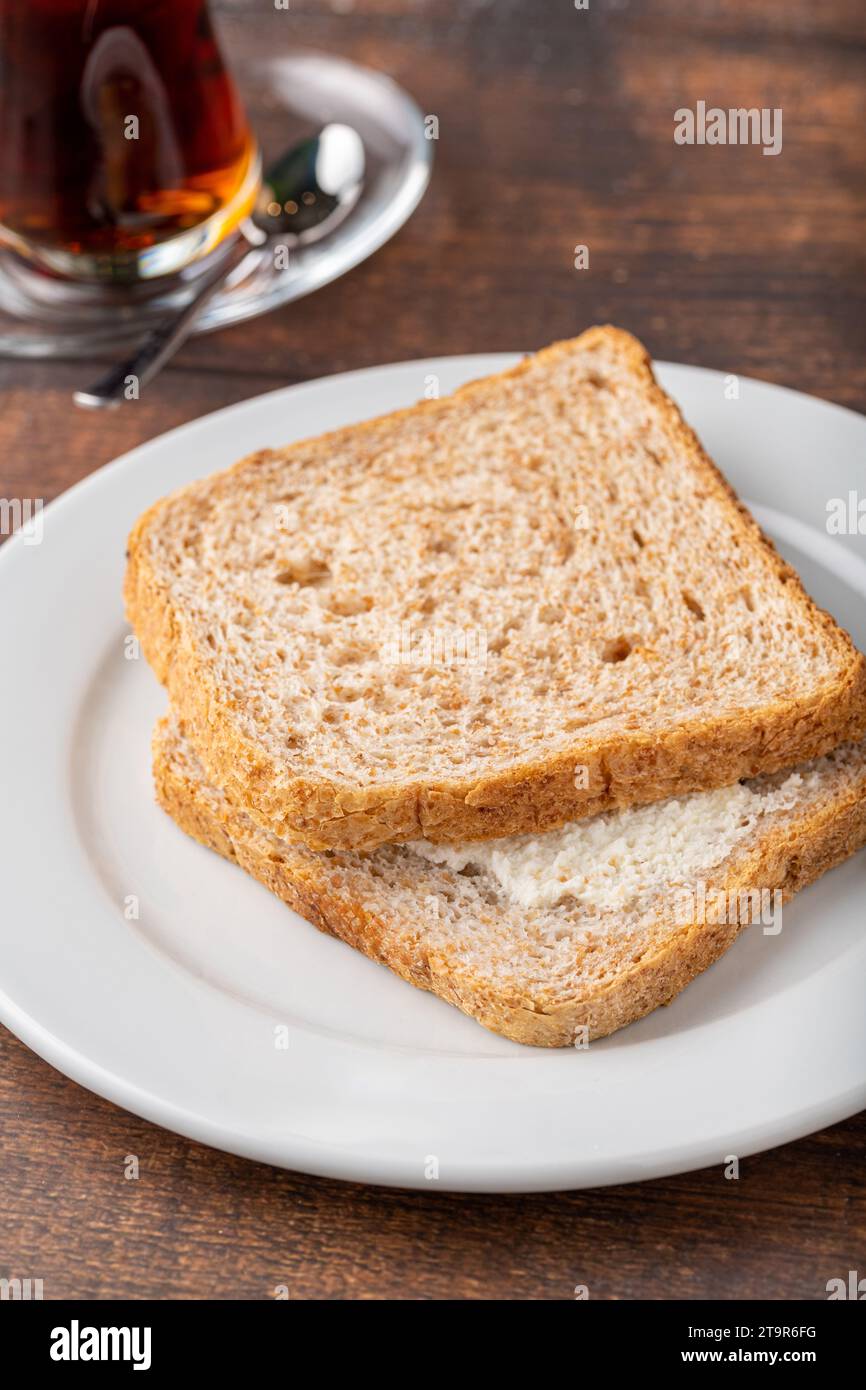 Sandwich con formaggio cremoso su piatto di porcellana bianca su un tavolo di legno Foto Stock