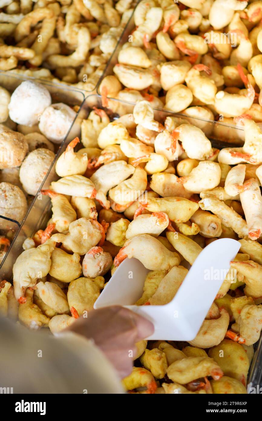 Vista ravvicinata verticale della mano bianca che porta i gamberetti precotti in un supermercato per la cena. Foto Stock