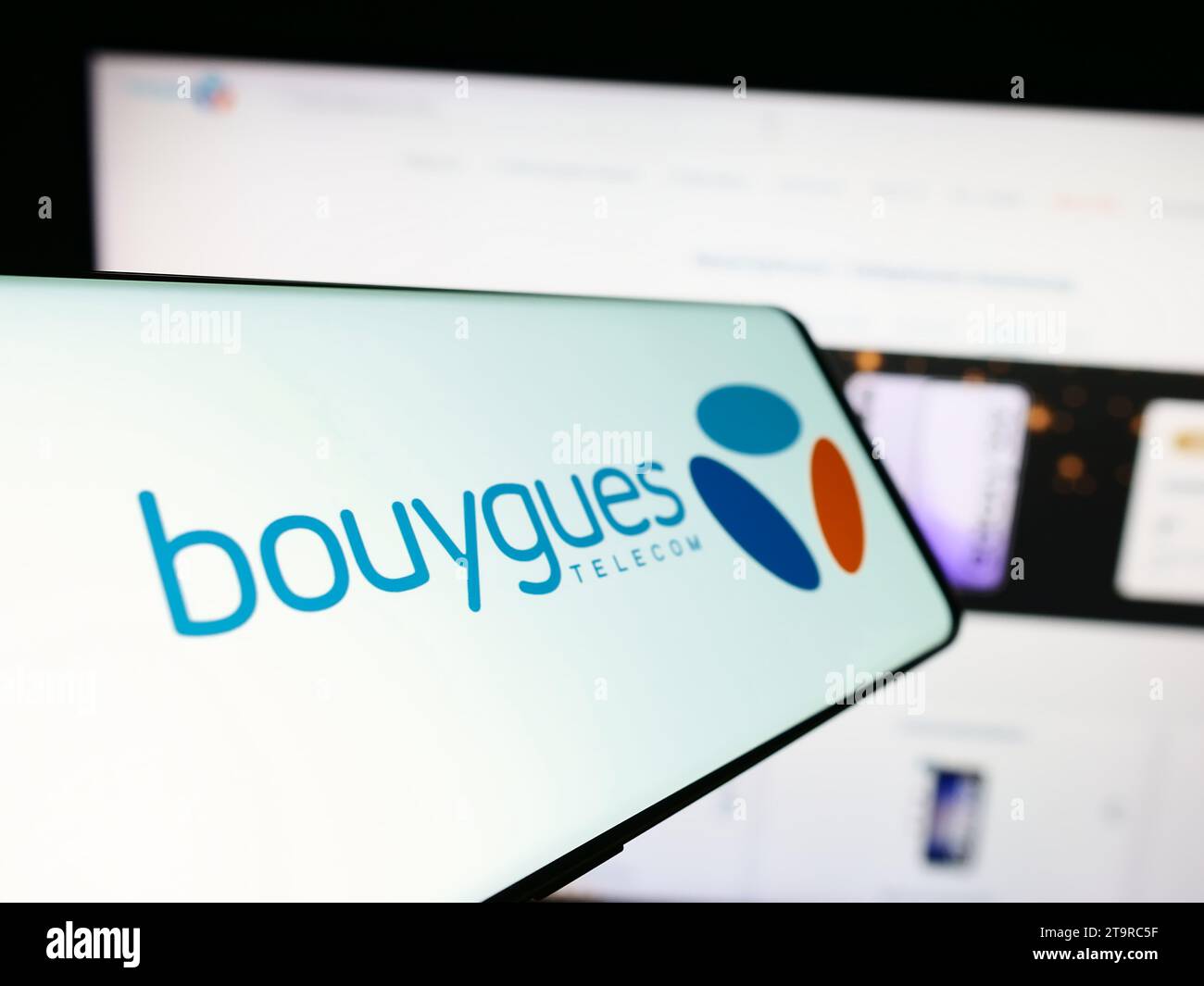 Smartphone con logo della società francese di telecomunicazioni Bouygues Telecom SA davanti al sito web. Mettere a fuoco il display centrale sinistro del telefono. Foto Stock