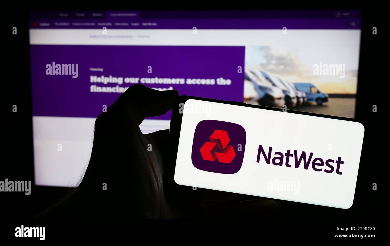 Persona in possesso di un cellulare con il logo della società finanziaria National Westminster Bank (NatWest) davanti alla pagina Web aziendale. Concentrarsi sul display del telefono. Foto Stock