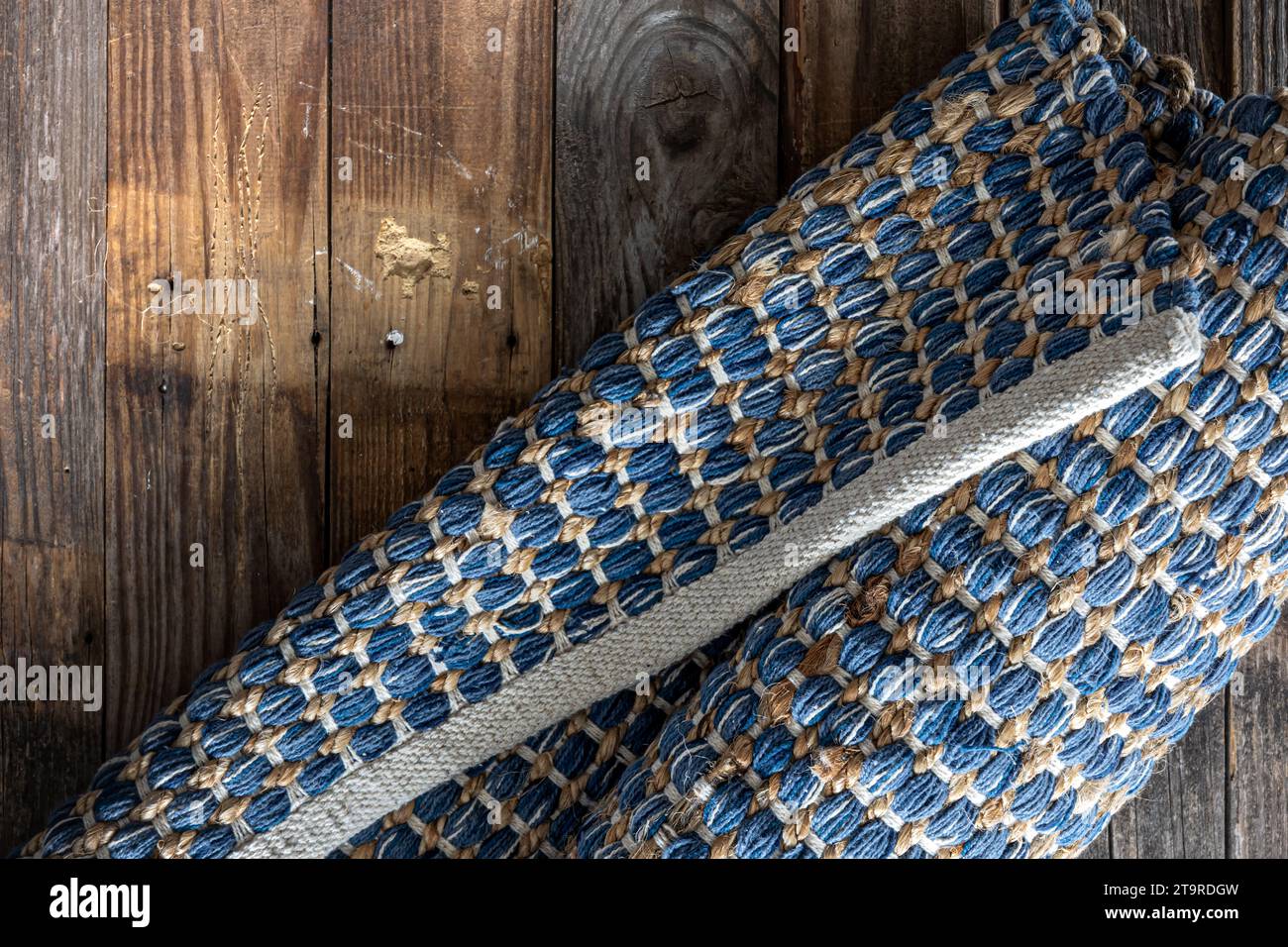 Tappeto in denim geometrico intrecciato a mano su pavimento in legno. Foto Stock
