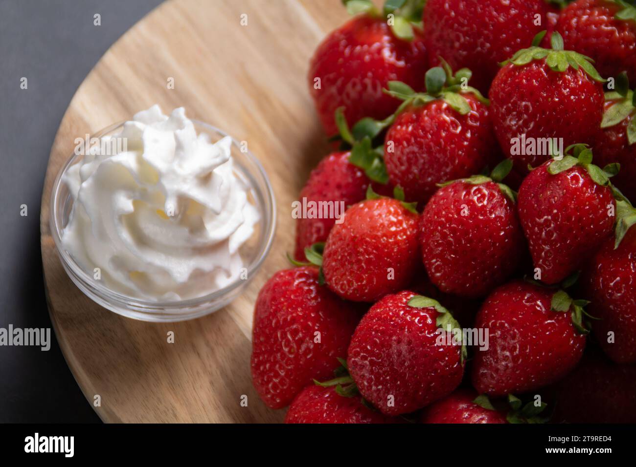 foto di fragole mature e crema su una tavola di legno, fresca, rossa, freschezza, appetitosa, tagliere Foto Stock