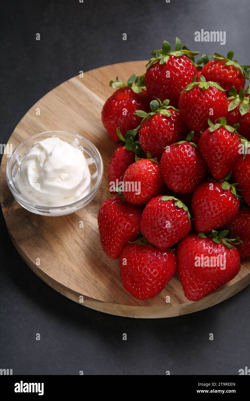 la foto mostra fragole fresche mature e succulente panna in un delizioso dessert. Questa delizia nutriente e piacevole mette in risalto i colori vivaci Foto Stock