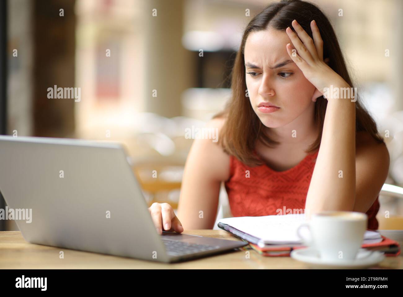 E-learning frustrato dagli studenti con un laptop in terrazza al ristorante Foto Stock