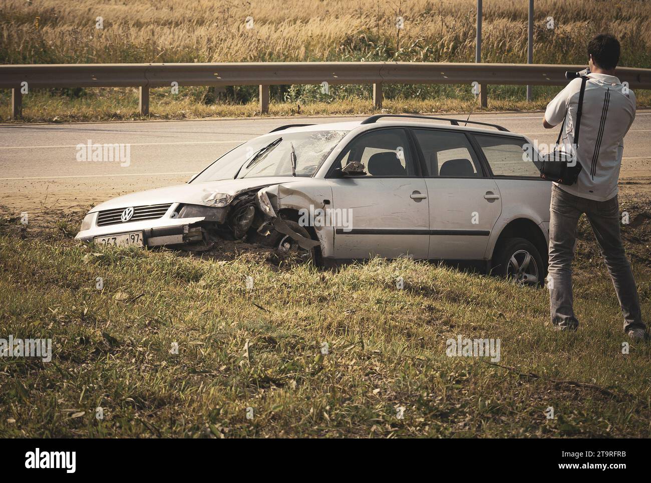 L'uomo spara all'auto rotta su una strada suburbana con una videocamera Foto Stock