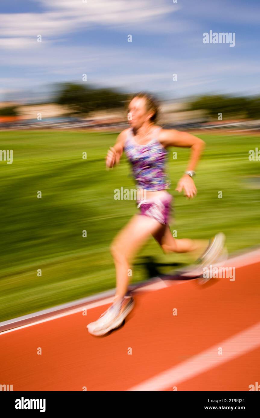 Una donna che corre in pista a Fort Collins, Colorado. (movimento sfocato) Foto Stock