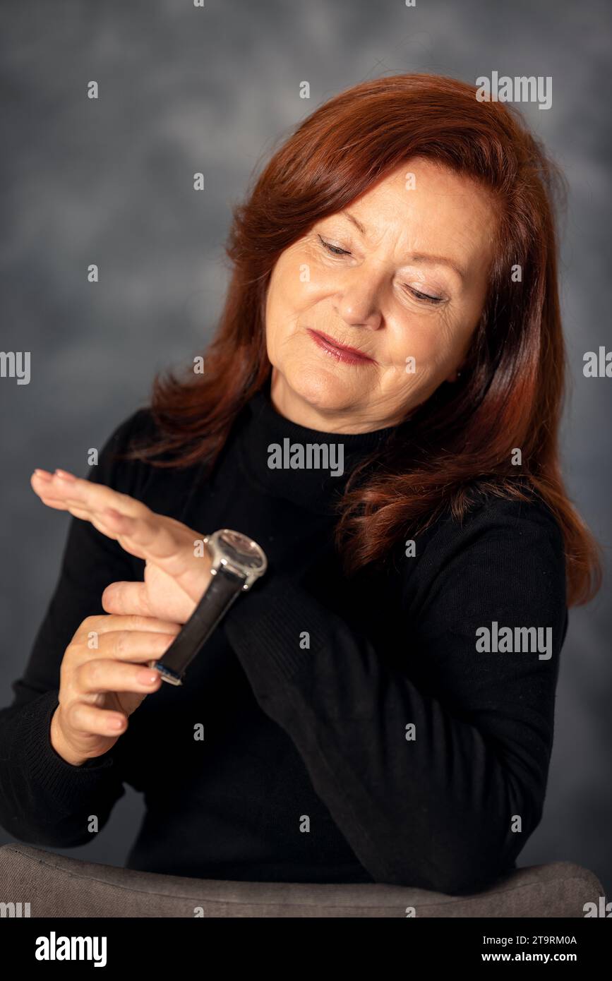 Ritratto di elegante donna di 60s anni su sfondo grigio. Donna matura di mezza età, elegante e sicura in europa Foto Stock