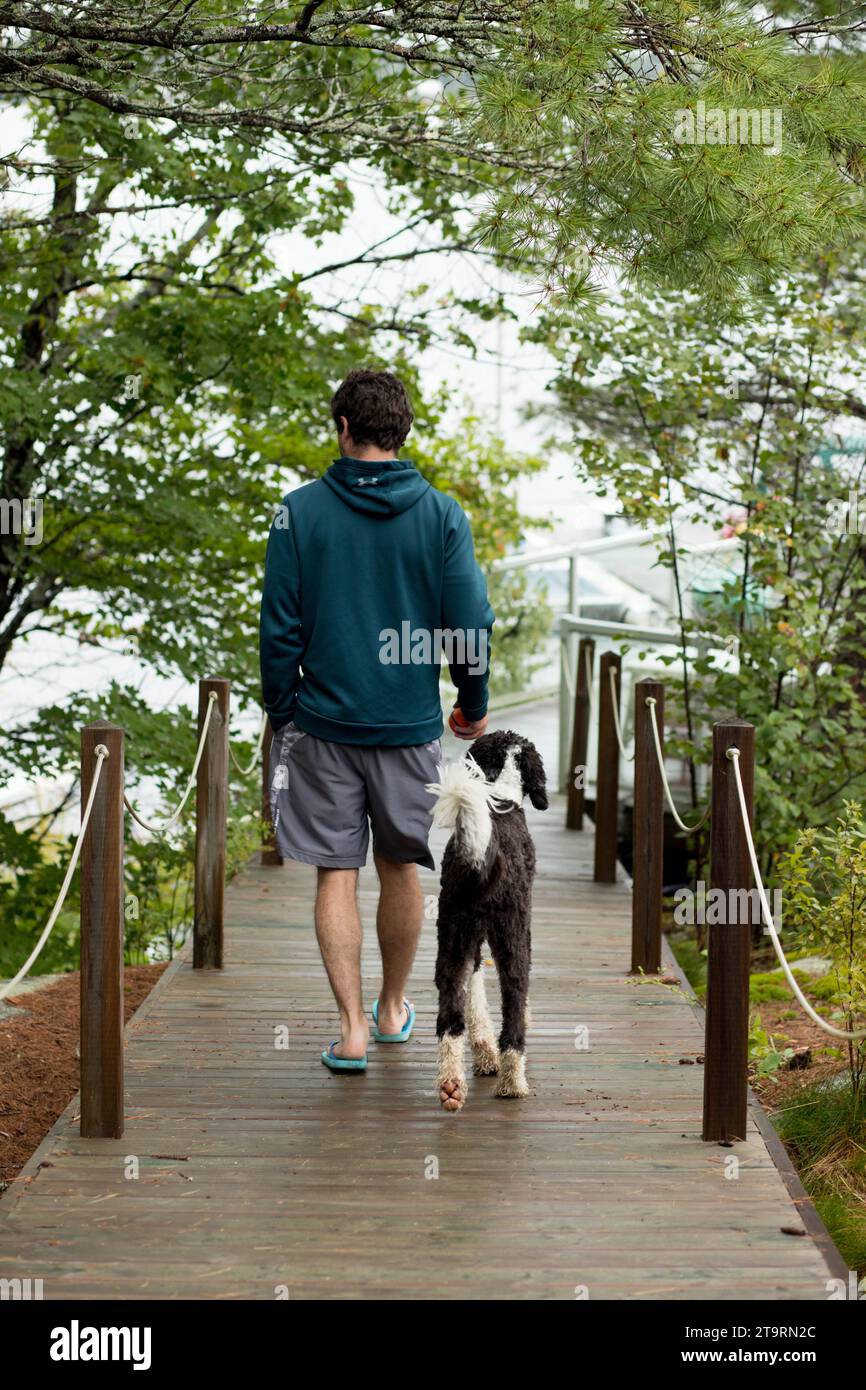 Vista posteriore del cane atletico che cammina con il proprietario al cottage Foto Stock