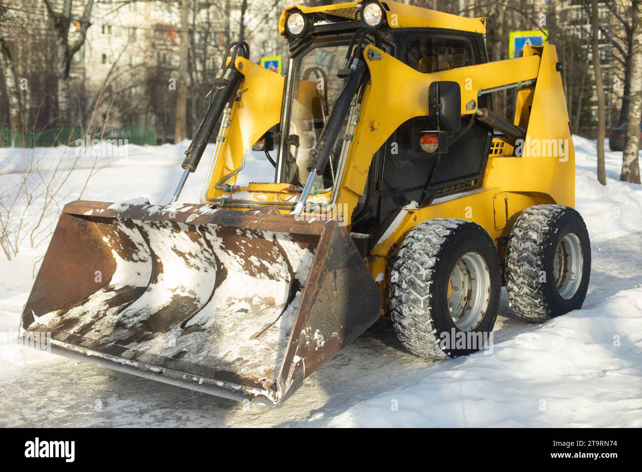 Attrezzatura per la raccolta della neve. Un trattore con benna. Foto Stock