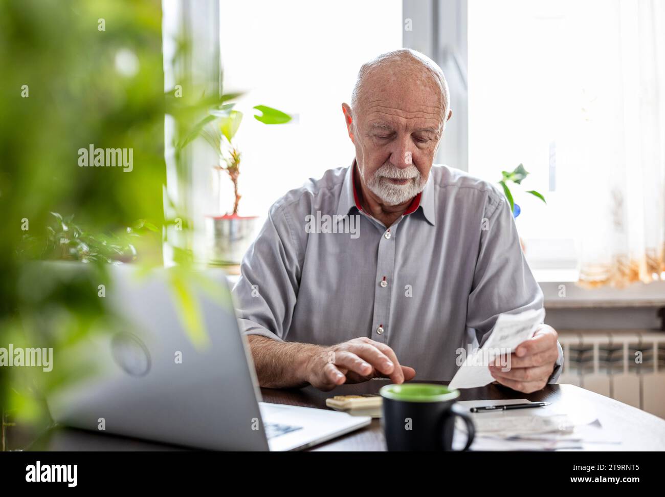 Un uomo anziano che controlla le sue finanze a casa Foto Stock