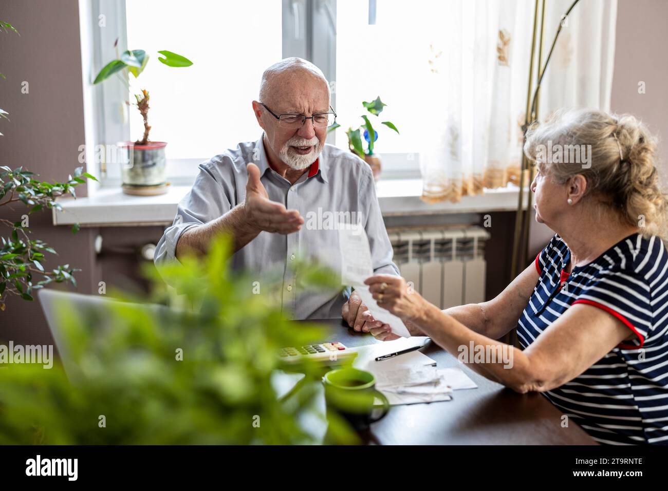 Coppia anziana che discute le proprie finanze domestiche mentre si siede al tavolo Foto Stock