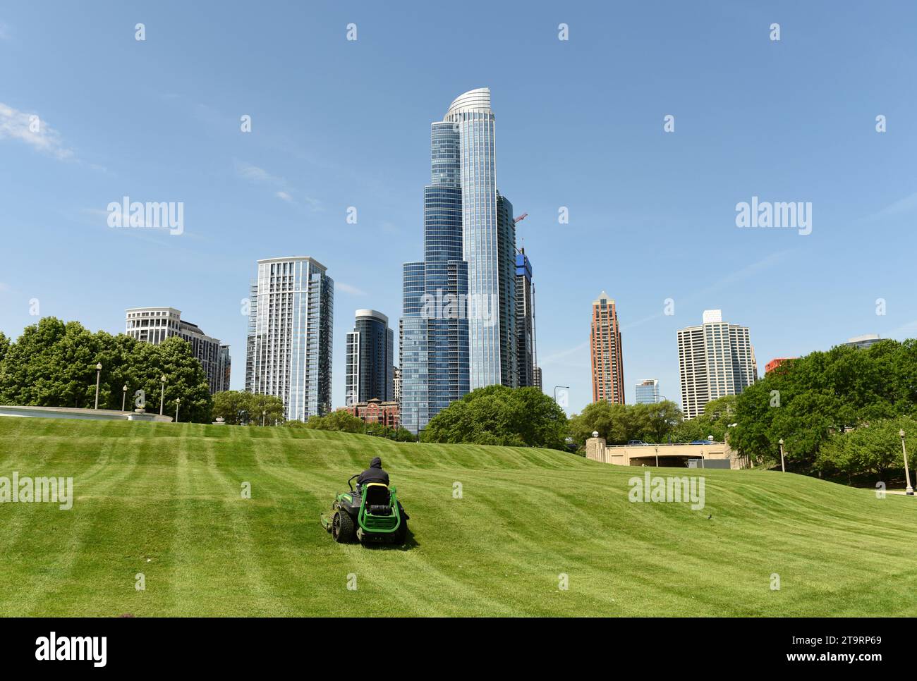 Lavoratore che taglia erba nel Great Ivy Lawn al Field Museum Park con grattacieli di Chicago sullo sfondo. Foto Stock