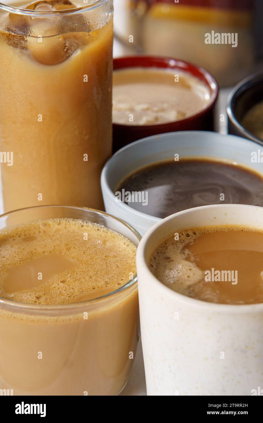 vista a 45 gradi di diversi caffè. Alcuni di loro hanno il latte, altri sono neri, caldi, ghiacciati, su una tovaglia bianca Foto Stock