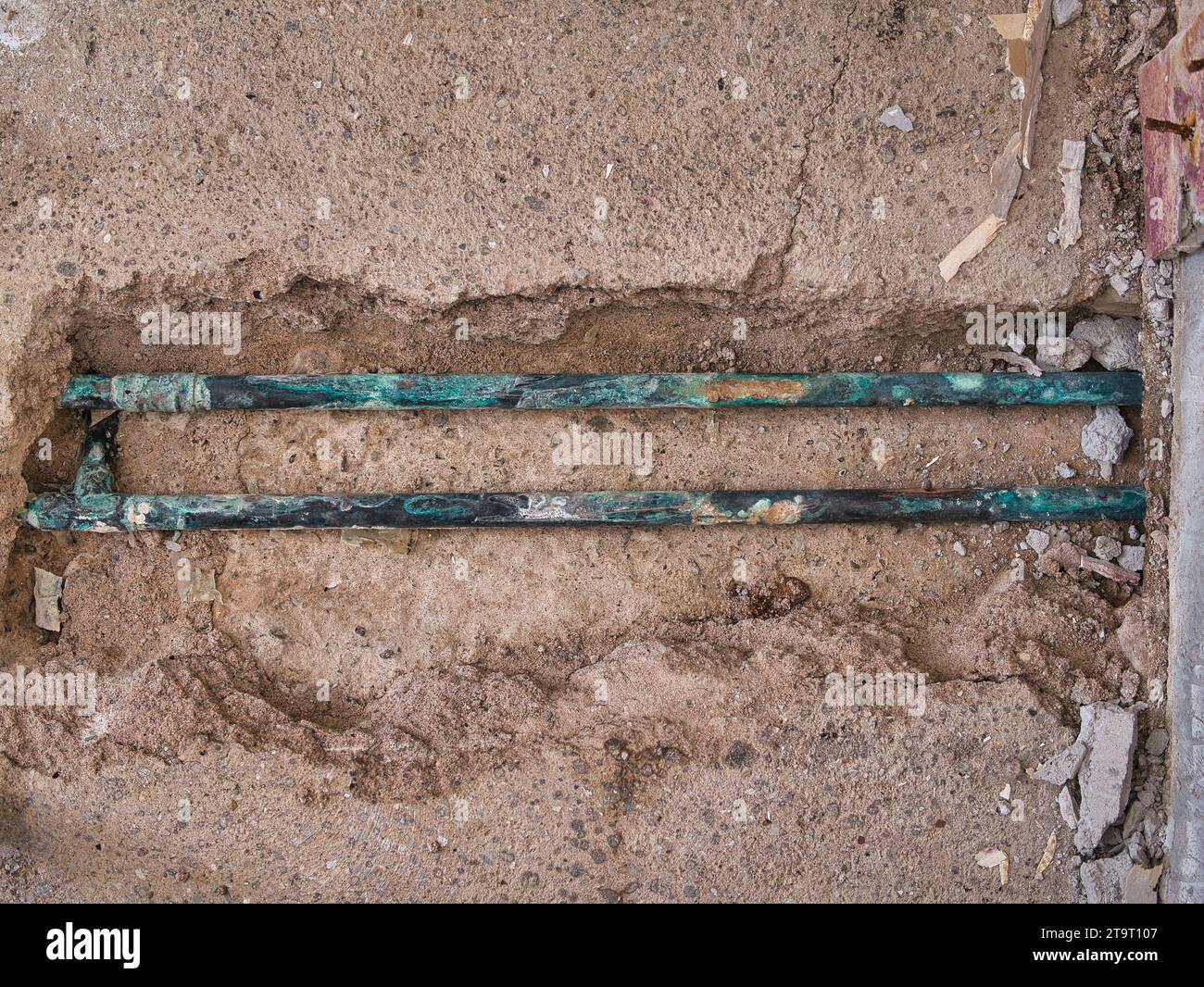 Tubi di riscaldamento centralizzati in rame esposti e con perdite, gravemente corrosi dopo essere stati sepolti nella lastra di cemento di una casa di circa 60 anni. Foto Stock