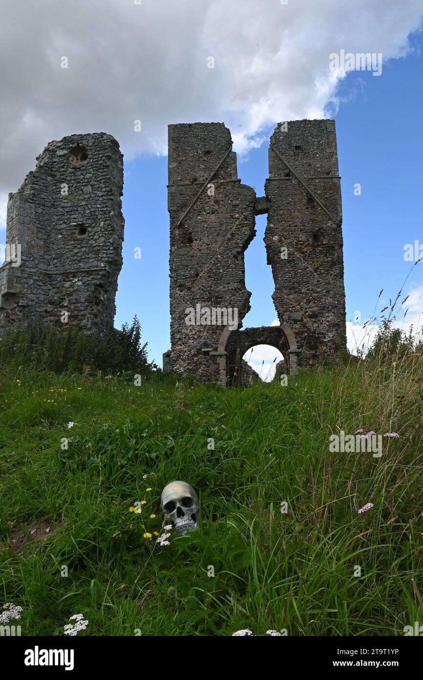 torre della chiesa in rovina con un teschio umano (replica) nell'erba in primo piano. Foto Stock