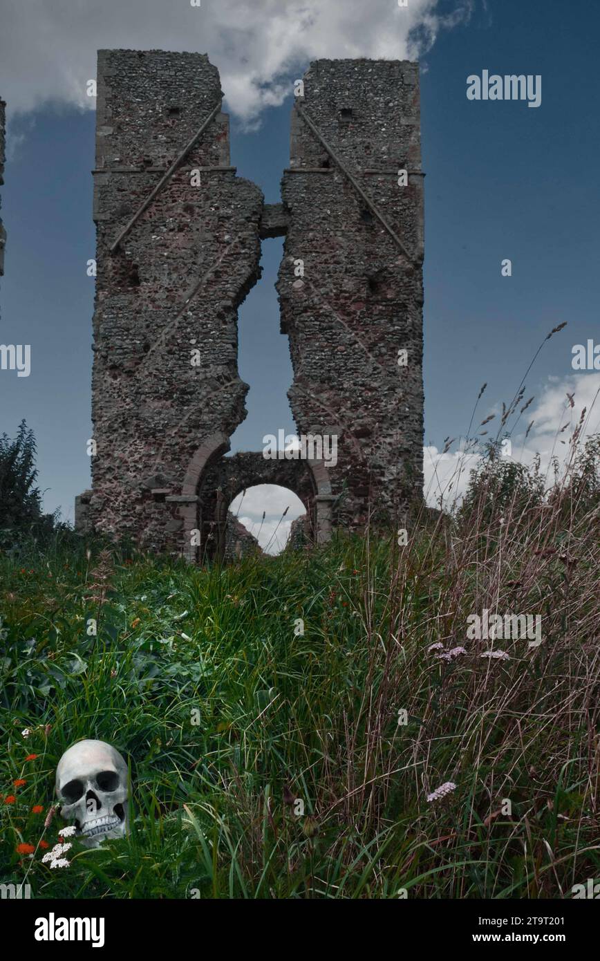torre della chiesa in rovina con un teschio umano (replica) nell'erba in primo piano. Foto Stock