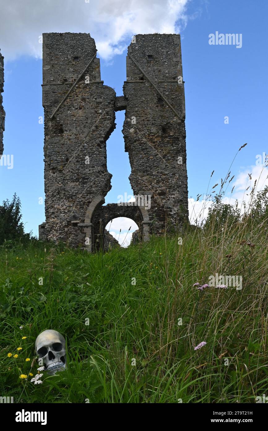torre della chiesa in rovina con un teschio umano (replica) nell'erba in primo piano. Foto Stock