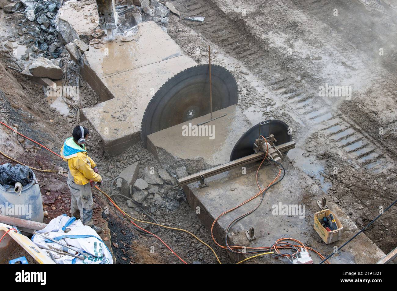 Demolizione di una base di cemento con una sega di cemento e un escavatore sulle rive del Reno, Colonia, Germania. Abriss eines Betonsockels mit Betonsae Foto Stock